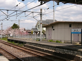線路内の向こうにコンクリートの信号機室と駅名標。