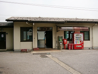 駅舎入口。焦げ茶のサッシの入口の横には公衆電話、ポスト、自動販売機があり、軒下に収まっている。